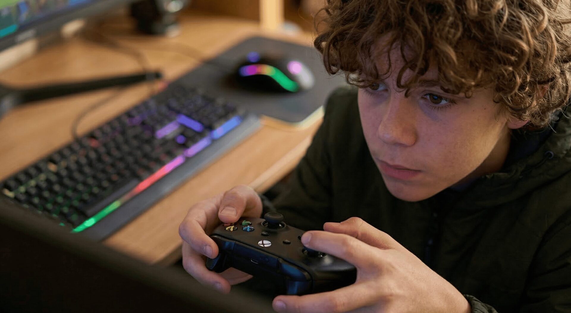 Teen holding a video game controller intent on the game he is playing.